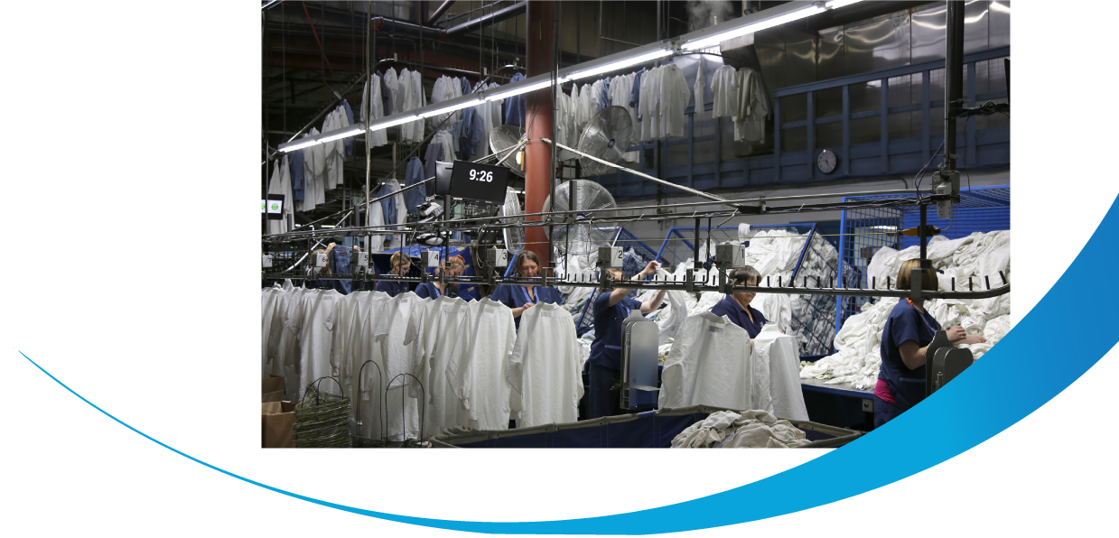 CITY laundering employees hanging hygienically clean frocks and other rental uniforms at the hangline.